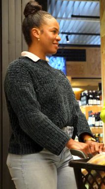 Profesyonel pazarlamacı kadın, marketin koridorunda glütensiz organik ürünler için kişiselleştirilmiş alışveriş rehberliği sağlıyor, müşterinin sağlıklı yaşam tarzı seçimlerini destekliyor.