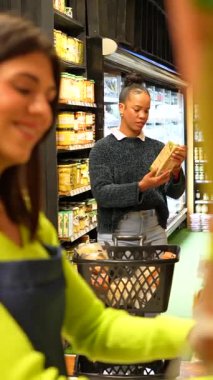 Organik ürün seçimi konusunda müşterilere rehberlik eden bilgili bir satıcı kadın, iyi stoklanmış süpermarket koridorlarında taze ve sağlıklı market seçeneklerini dikkatle inceliyor.