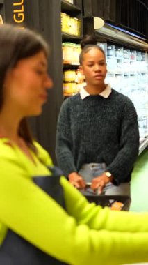 Süpermarket çalışanı, markette sağlıklı gıda seçeneklerini tartışarak alışverişe yardım ediyor.