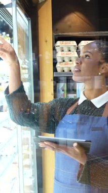 Soğutulmuş raflardan organik bakkaliyeleri dikkatlice seçen, sağlıklı beslenme odaklı mağazalarda sağlıklı besleyici ürünlere göz atan sağlıklı bir kadın.