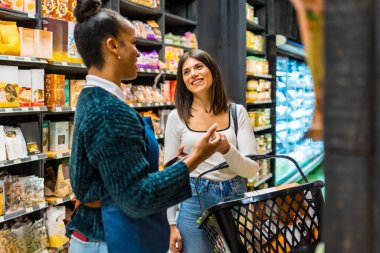 Gülümseyen satış elemanı müşterilere markette organik ve sağlıklı ürünlerle alışveriş yapmalarını tavsiye ediyor.