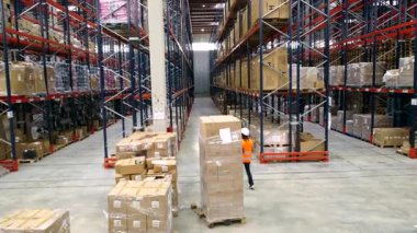 Lojistik operatörü depo koridorlarında geziniyor, envanter yönetiyor ve etkin işlemler sağlıyor