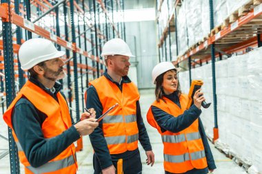 Depo çalışanları barkod tarayıcıları kullanıyor ve verimli envanter yönetimi için lojistik operasyonları sırasında özenle not alıyorlar.