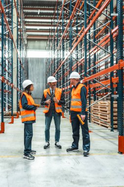 Depo çalışanları ve müdürleri büyük bir dağıtım merkezinde lojistik operasyonlar hakkında tartışıyorlar.