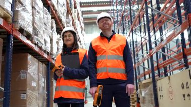 Depo çalışanları rafların arasında duruyor, ellerinde barkod okuyucu ve dosya var, kameraya gülümsüyorlar.