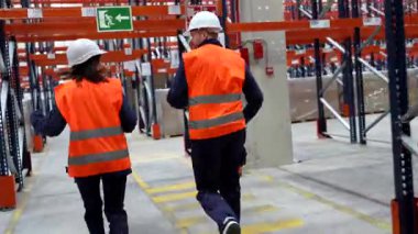 Lojistik işçileri depo koridorlarında hızla ilerliyorlar, profesyonel verimlilik ve koordineli takım çalışması ile yüksek tempolu dağıtım görevleri yürütüyorlar.