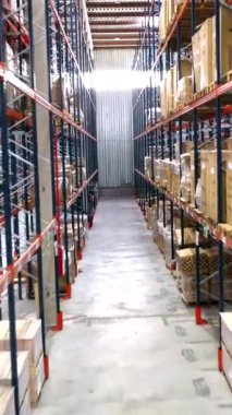Deponun içi karton kutular ve paketlenmiş paletlerle dolu raflarla dolu, dağıtılmaya hazır.