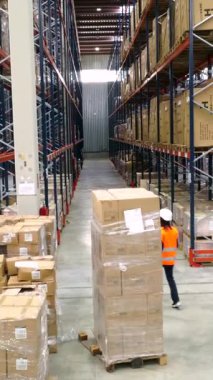 Lojistik işçisi büyük bir depoda paketleri tarıyor, envanteri yönetiyor ve etkin işlemler sağlıyor