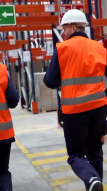 Profesyonel depo çalışanları acil çıkış kapısına doğru koşuşturuyorlar. Güvenlik eğitimi sırasında acil ve koordineli hareket ediyorlar.
