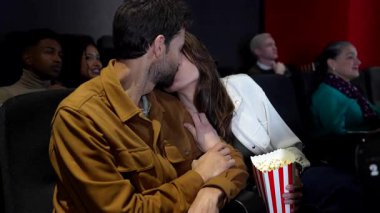 Sevecen bir çift sinemada patlamış mısır ve 3 boyutlu bir film izliyor, diğer izleyicilerle çevrili.