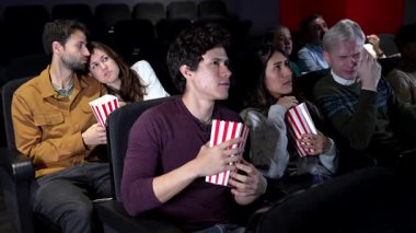 Arkadaşlar korku filmlerini izlerken yoğun tepki veriyorlar, loş sinemada patlamış mısırları büyük ekranla paylaşıyorlar, kolektif duygusal deneyimleri ortaya çıkarıyorlar.