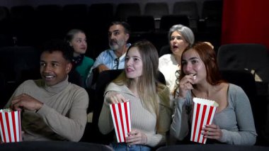 Genç çok ırklı çift film tecrübelerini paylaşıyor, patlamış mısır paylaşıyor ve üç boyutlu gözlük takıyor.