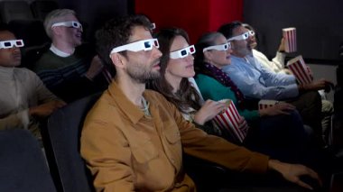 Genç, çeşitli arkadaşlar, özel gözlük takarak ve karanlık sinema salonunda patlamış mısır paylaşarak 3 boyutlu film deneyiminin tadını çıkarıyorlar.