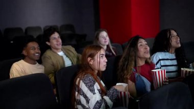 Bir grup farklı arkadaş gülerek ve tezahürat yaparak, 3D film gösterimi sırasında çeşitli duygular deneyimlediler.