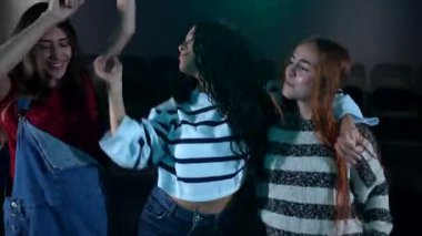 Üç boyutlu film gösterimi sırasında heyecanla dans eden arkadaşlar, sinemada eğlenceli anlar paylaşırken birlikte eğlenceli eğlence deneyimlerinin tadını çıkarıyorlar.