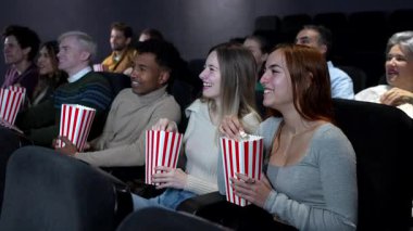 Çeşitli genç arkadaşlar gülüyor, patlamış mısırlarını paylaşıyor, karanlık tiyatro salonunda 3 boyutlu sinema sihrini deneyimliyorlar.