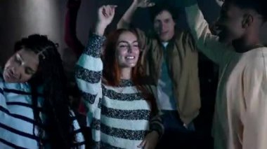 Loş bir sinemada yüksek enerjiyle dans eden arkadaşlar, neşeli disko partileri sırasında bulaşıcı ritmik hareketlerle neşeli anlar paylaşıyorlar.
