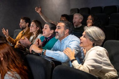 Çeşitli yaşlardaki coşkulu sinemacılar, film deneyimine tamamen bağlı olarak tezahürat ve alkış yapıyorlar.