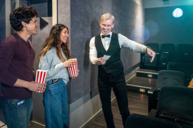 Genç çift ellerinde patlamış mısır kovalarıyla sinemada yerlerini gösteriyorlar. Filmin tadını çıkarmaya hazırlar.