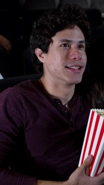 Sinemada romantik bir akşam, genç çift patlamış mısırlarını paylaşırken üç boyutlu film izliyor, ortak eğlence ve bağlantının tadını çıkarıyor.