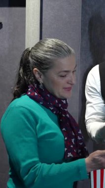 Profesyonel sinema teşrifatçısı, gösterişli özel gösterim odasındaki koltukları göstererek müşteri hizmetlerine dostça bir tavır sergiliyor.