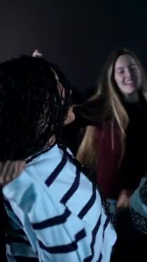 Dans eden genç insanlar, karanlık tiyatroda üç boyutlu film projeksiyonu sırasında ortak bir neşeyi paylaşıyorlar, kolektif heyecan ve arkadaşlığı ifade ediyorlar.