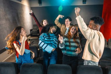 Sinema salonundaki disko etkinliği sırasında dans eden ve müzikten hoşlanan neşeli çoklu etnik arkadaşlar.