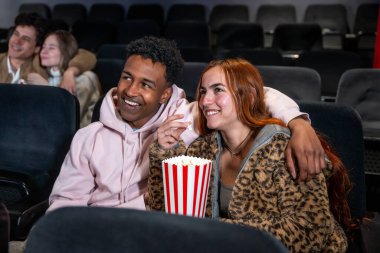 Mutlu çift sinemada film izlerken patlamış mısır paylaşıyor, arkadaşlarıyla eğleniyor.