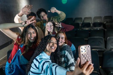 Bir grup güler yüzlü arkadaş sinemada selfie çekiyor, film gecesinde eğleniyorlar.