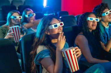 Bir grup arkadaş 3D gözlük takıyor sinemada film izliyor, patlamış mısır yiyor ve eğleniyorlar.