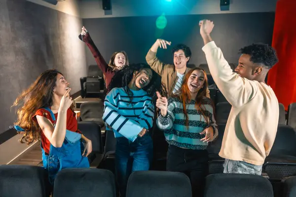 Sinema salonundaki disko etkinliği sırasında dans eden ve müzikten hoşlanan neşeli çoklu etnik arkadaşlar.
