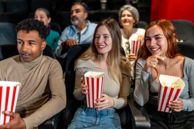 Birlikte film izleyip patlamış mısır yiyen, sinemada eğlenen çok uluslu arkadaşlar.