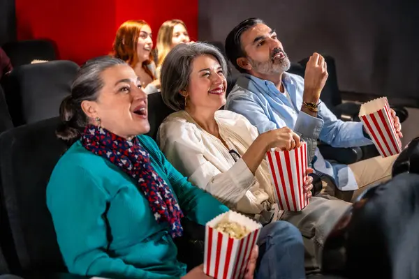 Samimi bir tiyatroda eğlenen arkadaş grupları, sinemanın içine dalmışken kahkaha ve patlamış mısır paylaşıyorlar.