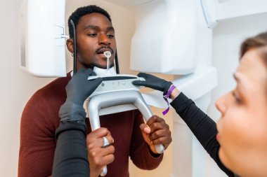 Dişçi modern bir diş kliniğinde erkek hasta için panoramik diş röntgeni taraması hazırlıyor.
