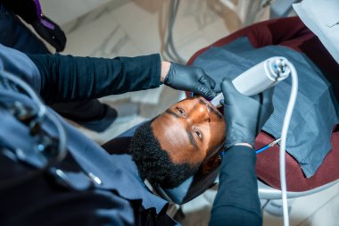 Diş hekimi profesyonel bir diş beyazlatma lambası kullanır. Bir sanat kliniğinde hastanın gülümsemesini arttırır.