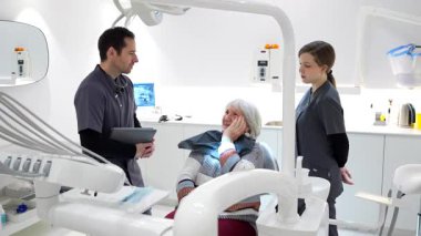 Diş hekimindeki dişçi ve hemşireye diş ağrısını açıklayan son sınıf öğrencisi.
