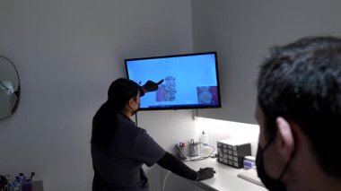 Profesyonel dişçi, hastanın 3D diş taramasını tıbbi not monitöründe analiz ediyor. Detaylı oral sağlık muayenesi sırasında gelişmiş dijital dişçilik teknolojisi gösteriyor.