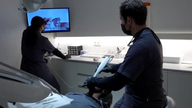 Diş hekimi, modern bir diş kliniğinde hastanın dişlerinin dijital taramasını yapıyor.