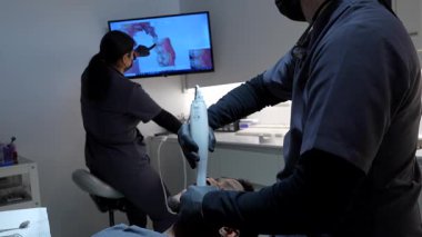 Diş hekimi, modern bir diş kliniğinde hastanın dişlerinin dijital taramasını yapıyor.