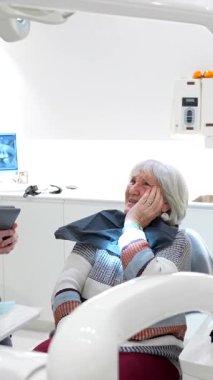 Üst düzey kadın dişçiyle tedavi seçeneklerini tartışıyor, modern diş kliniği ortamını ve hasta etkileşimini sergiliyor