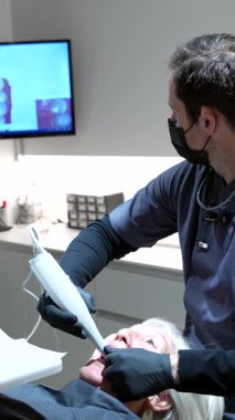 Diş hekimi, hastanın dişlerinin dijital taramasını yapıyor. İntraoral tarayıcı kullanarak, monitörde 3D model gösteriyor.