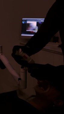 Diş hekimi beyazlatma jeli uyguluyor ve diş beyazlatma işlemi için modern diş kliniğinde UV lambası kullanıyor.