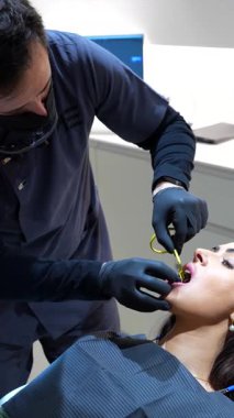 Modern klinik ortamda hastanın oral sağlığını titizlikle değerlendirirken gelişmiş x ışını teknolojisini kullanarak kapsamlı diş muayenesi yapan deneyimli bir diş hekimi.