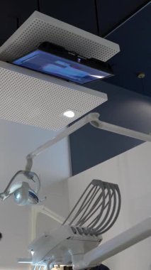 Dişçi koltuğunda yatan hasta, modern bir diş kliniğinde bir dişçiden tedavi görüyor.