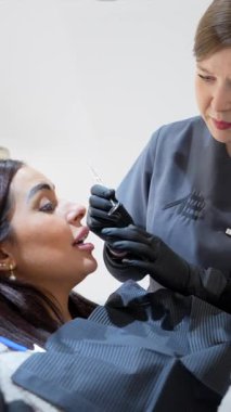 Modern klinik ortamında diş muayenesi sırasında hastaya tıbbi prosedürü dikkatlice açıklayan profesyonel dişçi, oral sağlık iletişimi ve tedavi ayrıntılarına odaklanıyor