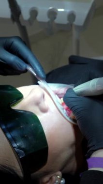 Modern diş kliniğinde diş beyazlatma jelini dikkatlice uygulayan profesyonel diş hekimi, hastanın oral sağlığı ve güzellik iyileştirmesine odaklanır.