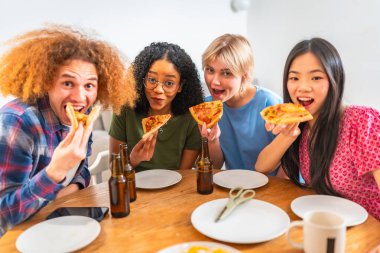 Bir grup genç arkadaş pizza yiyor ve bira içiyor, evde birlikte eğleniyorlar.