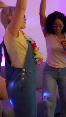 Genç kadınlar canlı karaoke anlarını paylaşıyor, renkli disko ışıklarıyla enerjik bir şekilde dans ediyor ve şarkı söyleyip kaynaşıyorlar.