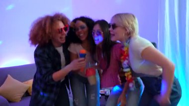 Enerjik bayan arkadaşlar renkli disko ışıklarıyla canlı ev partileri sırasında karaoke yaparak, kahkahaları, içkileri ve müziği paylaşarak eğleniyorlar.