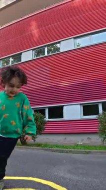 Enerjik anaokulu öğrencisi seksek oynamayı seviyor, okul bahçesindeki renkli işaretlerle sıçrayıp dengelemeyi, fiziksel aktiviteyi ve koordinasyonu teşvik etmeyi.